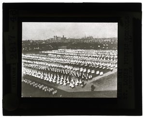Foto orizzontale in bianco e nero di centinaia di scolari allineati in formazione per la parata e il corteo del Field Day. Tutte le ragazze in abiti bianchi e i ragazzi in camicie bianche e cravatte con pantaloni scuri da Unbekannt Unbekannt